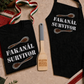 Fakanal Survivor Superpack with T-shirt, one-size apron, and Weapon of Mass Education wooden spoon on a light sand background
