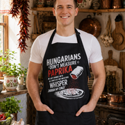 Fit clean-shaven Hungarian man wearing the Paprika apron in a rustic Hungarian kitchen